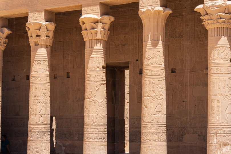 一位女士走过一座有柱子和支柱的古建筑