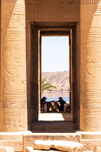 一个人坐在一座古老寺庙的门口 俯瞰着一个湖泊。