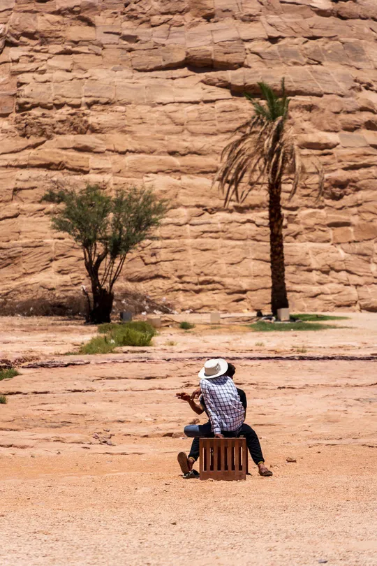 一个坐在沙漠中的长椅上 背景是岩石的男人