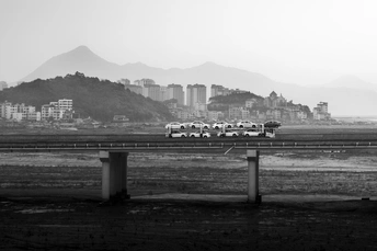 一张黑白照片 背景是一座城市 公路边停着汽车。