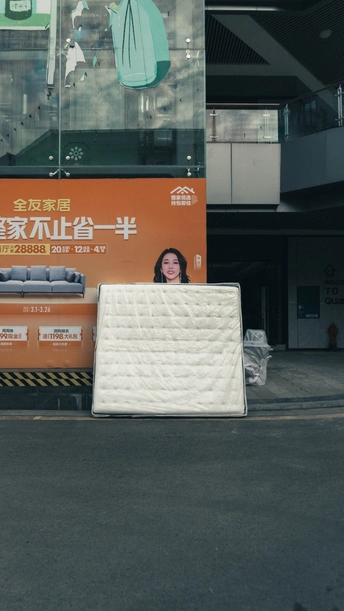 路边的建筑旁有一块广告牌 一辆大床垫停在路边。