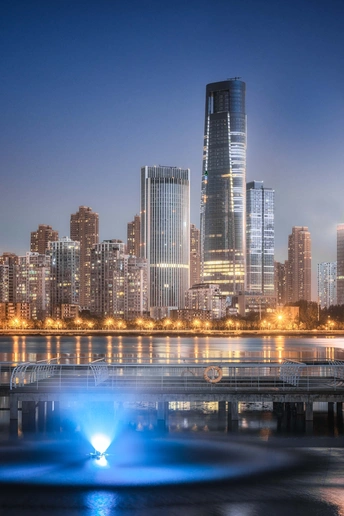 夜晚的城市 高大的建筑 河上有喷泉 喷泉位于天际线前