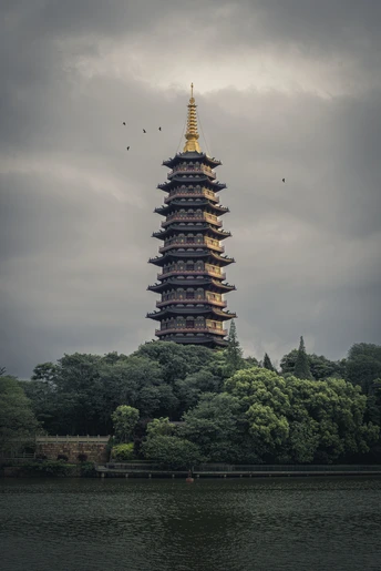 湖中一座大型宝塔 云雾缭绕的天空中有鸟儿飞翔。