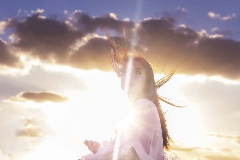 站在有云和太阳的天空下的年轻女子