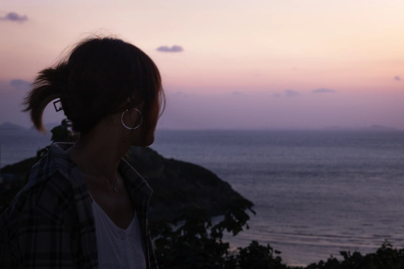 一位年轻男子和女子站在一个俯瞰湖泊的山丘上 当太阳落山于海洋之上。