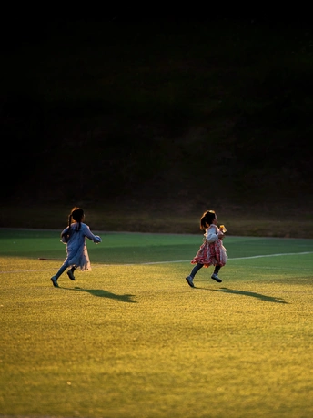 年轻女孩们在草地上踢足球 当第三个孩子走过时 她们在草地上奔跑。