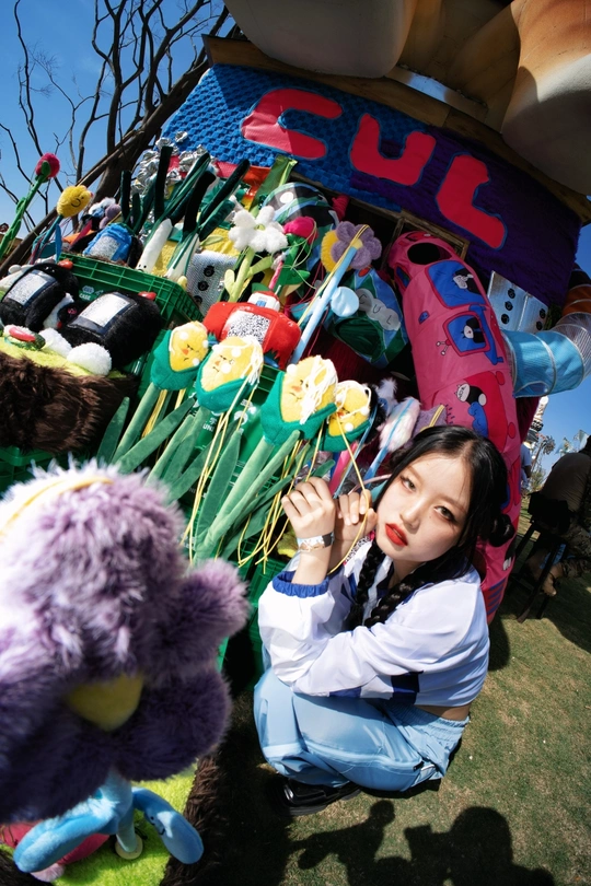 一个小女孩在气球、花、玩具和填充动物的展示前摆姿势拍照。
