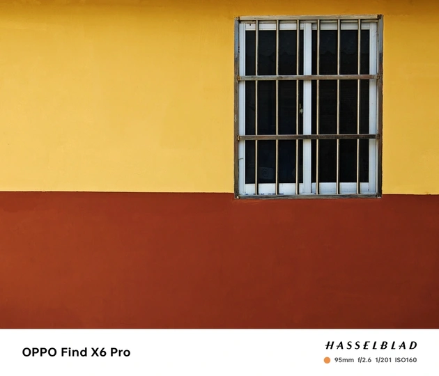 一个橙色、黄色和红色的建筑物的彩色墙壁上的带有栏杆的窗户