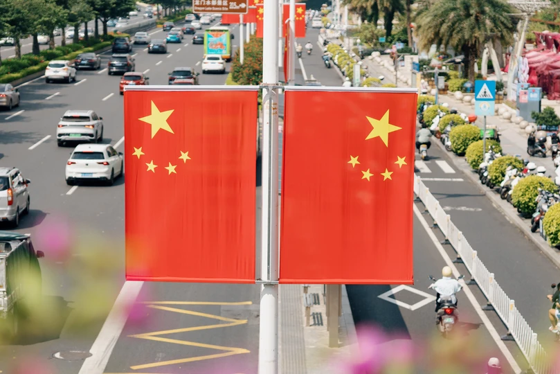 一面挂有六颗星的红旗 飘扬在繁忙的汽车街道上方。