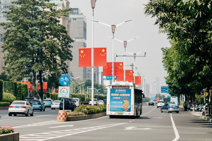 一条街道上有汽车、公交车、标志和旗帜沿着道路行驶。