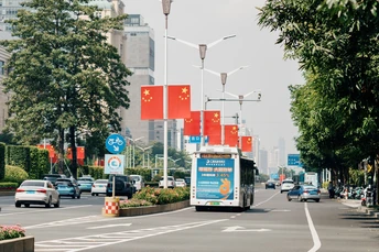 一条街道上有汽车、公交车、标志和旗帜沿着道路行驶。