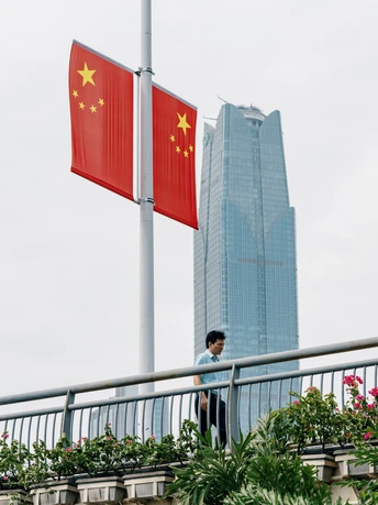 站在桥上的人正在看一幢高楼前面的红旗飘扬。