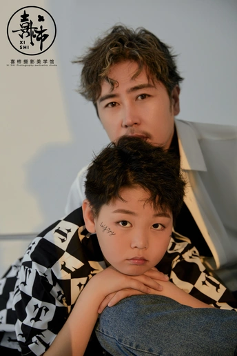 一个有纹身的男孩坐在一个男人旁边