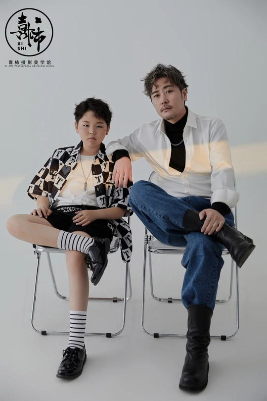 一位年轻男子和一位年轻女子与一个坐在椅子上的男孩一起拍照。