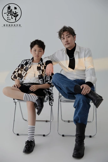 一位年轻男子和一位年轻女子与一个坐在椅子上的男孩一起拍照。