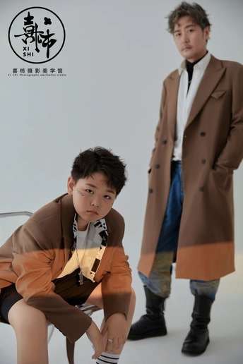 一个年轻的男孩坐在一位男士旁边的一把椅子上。