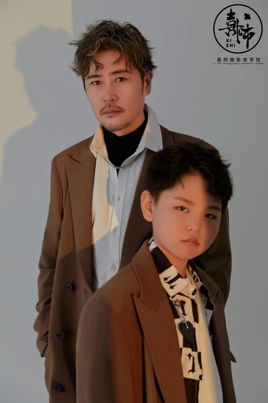 一个穿着棕色外套的年轻男孩站在一个穿西装的男人旁边