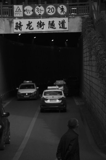 夜晚的黑暗隧道 路边停着车 一个人在隧道里走。