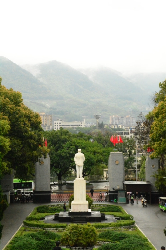 中间有白色纪念碑的大型广场 周围有公园、人群、建筑、山峦作为背景。