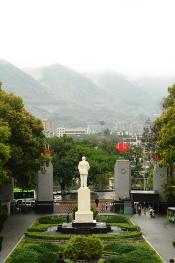 中间有白色纪念碑的大型广场 周围有公园、人群、建筑、山峦作为背景。