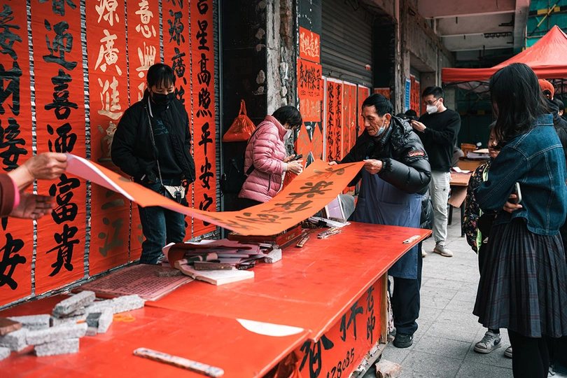 一位站在街边 旁边是红色桌子的一名妇女