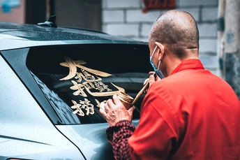 一个穿红衬衫的男子站在一辆车旁边