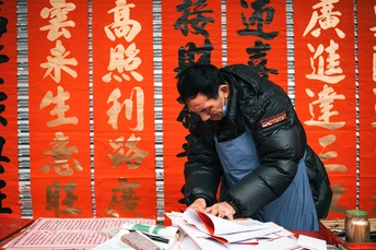 当一名男子站在一张带有文字的桌子旁边时 一名女子用剪刀剪纸。