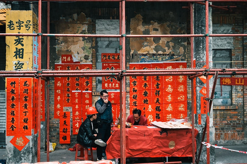 一些男人站在一栋建筑前 建筑上有红色标志。