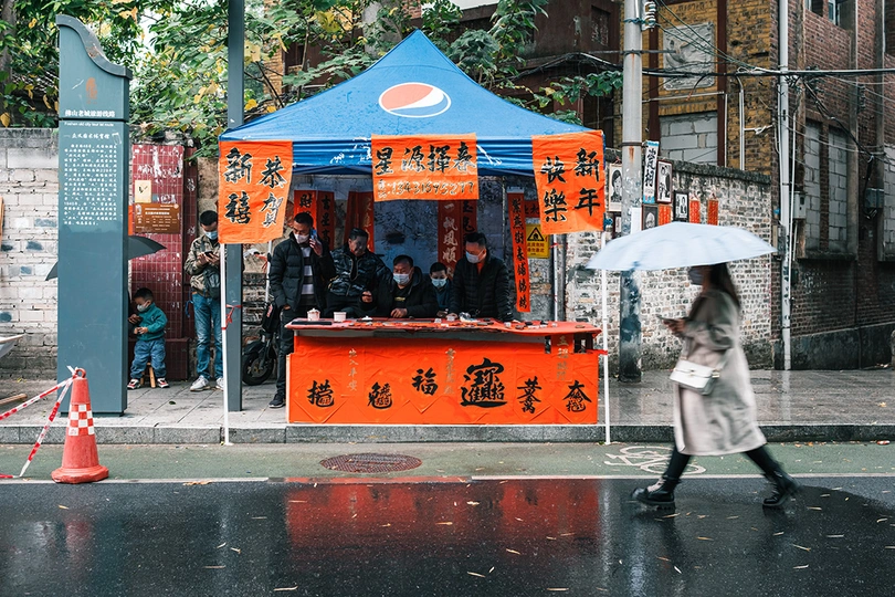 一位女士在雨中走在湿漉漉的人行道上 手里拿着一把蓝色雨伞。