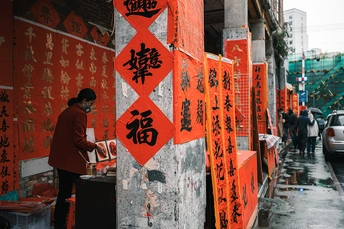 一个人站在人行道上 前面有一栋带有红色标牌的建筑物 上面有亚洲文字。