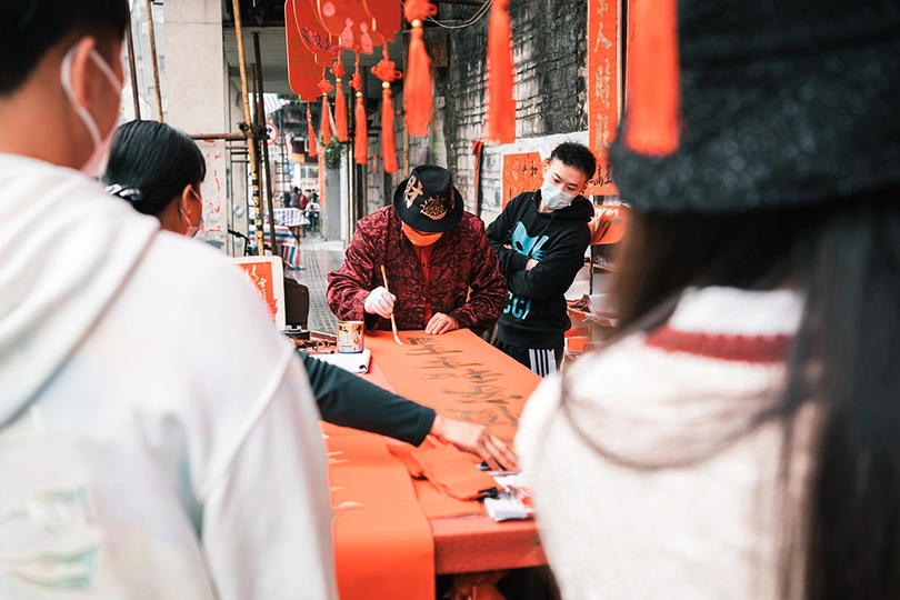 戴面具的女人站在一张红色的桌子旁边