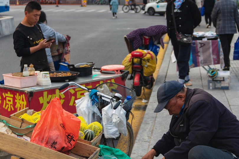 一个人推着木头车 停在有食品盒的街道旁边的人行道上。
