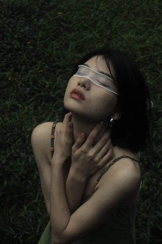 一个戴眼镜的年轻女子躺在草地上 双手捂住脸