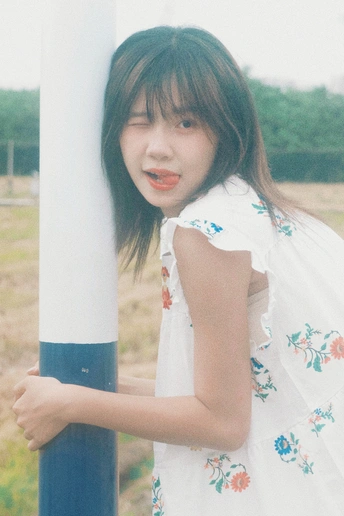 一位穿着白色连衣裙的小女孩紧紧抓住一根白色杆子