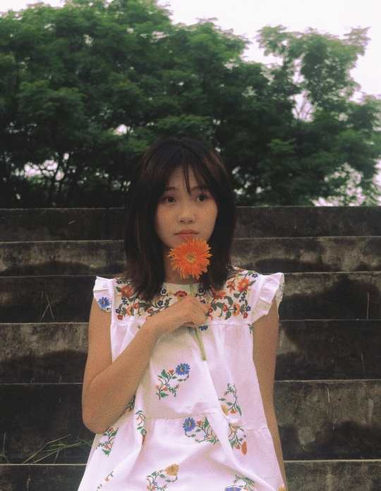 一个小女孩穿着裙子手里拿着一朵小花