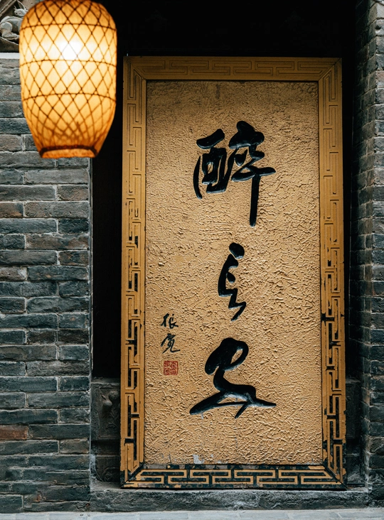 一幢有中文书写的墙壁上的老建筑 门上挂着灯笼和一盏灯。