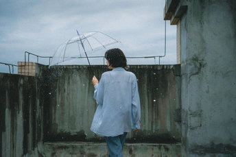 一位穿蓝色雨衣的女人站在雨中 在雨伞下。