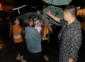 一家抱着婴儿和绿色雨伞在夜晚站在雨中