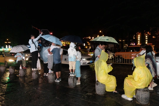 一些人穿着雨衣 手里拿着雨伞。