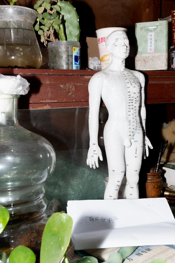 一座小洋娃娃的雕像 sits next to a white paper on a shelf.