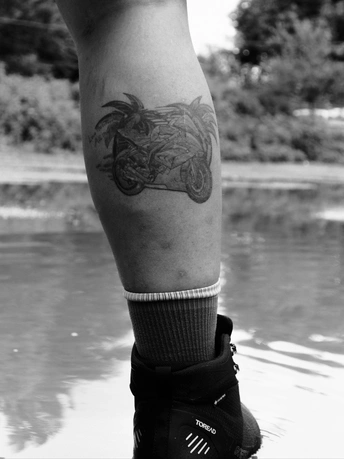 一位有黑白纹身的大腿和小腿靠近水的男子