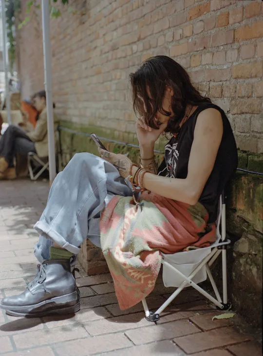 一个年轻女子坐在椅子上看着手机 另一个人坐在外面。