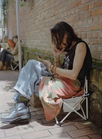 一个年轻女子坐在椅子上看着手机 另一个人坐在外面。