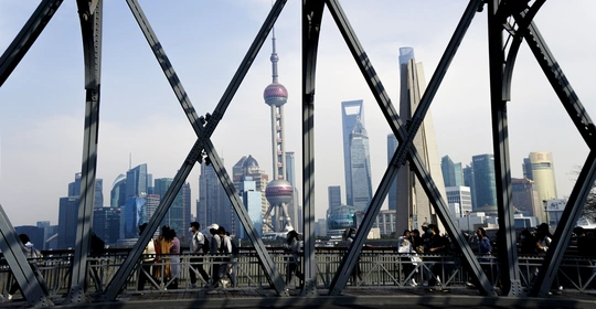 行人穿过一座桥 背景是建筑物和塔楼的天际线。