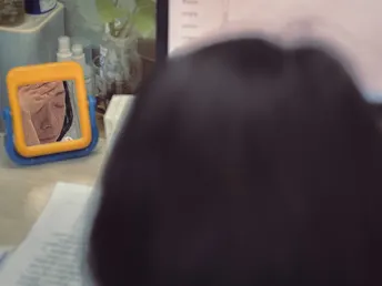 一个人坐在桌子旁 正在查看电脑屏幕并拍照。