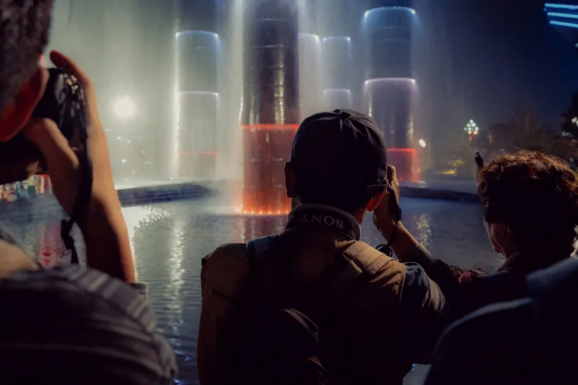 游客在前景有喷泉的夜晚拍摄场景