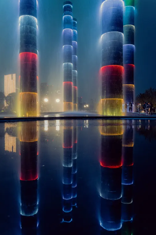 夜晚时 喷泉被五彩斑斓的灯光和水上柱子照亮。