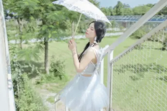 一位穿着白色连衣裙的年轻女子拿着雨伞