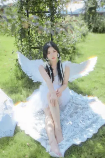 一个坐在草地上 毯子上的白色翅膀女孩 树下