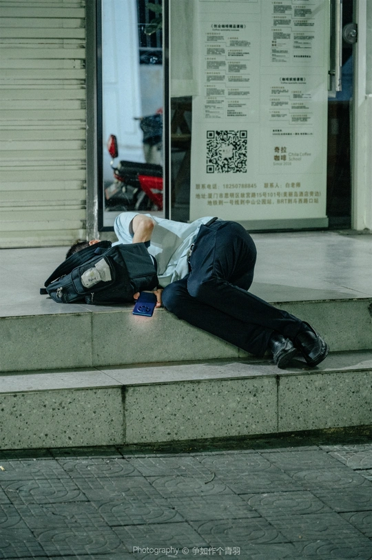 一个人在建筑物前的人行道上睡觉 人行道上躺着一个人。